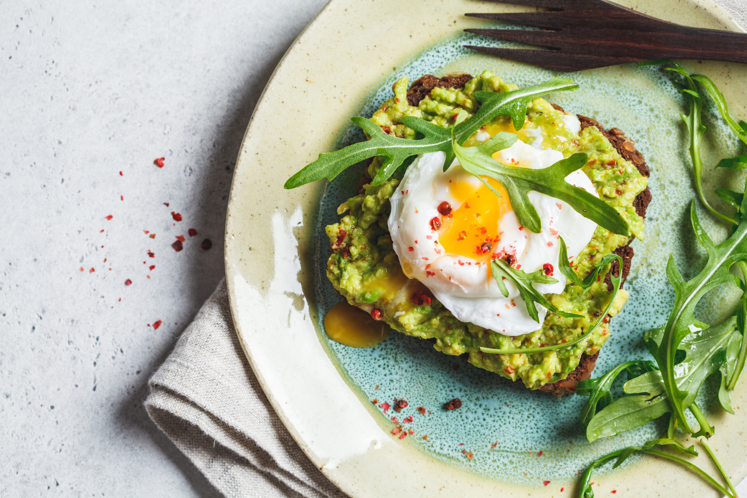 Avocado and poached egg toast on rye bread, top view.