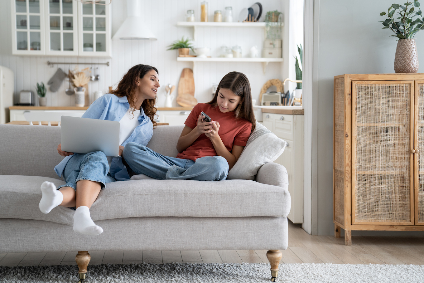 Mom and teen on couch with phone and laptop