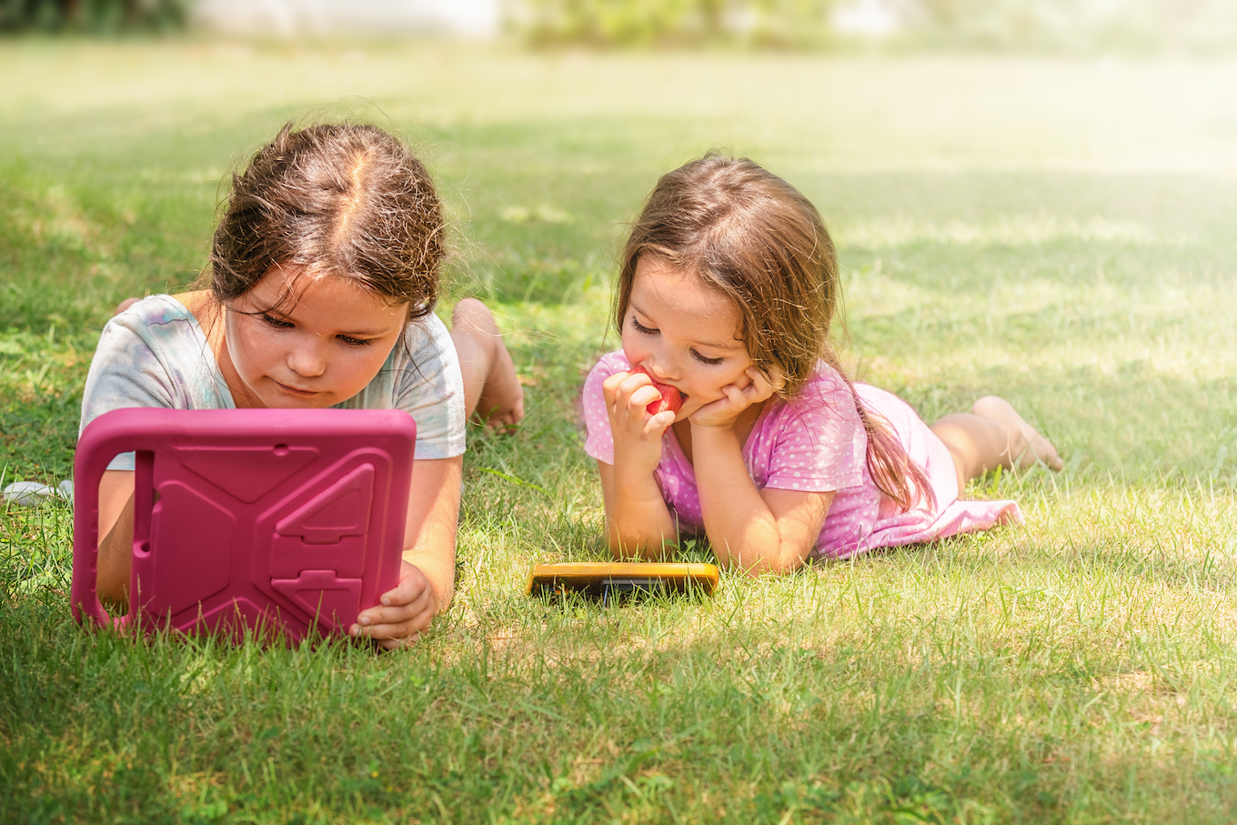 Children playing tablet and phone in the backyard