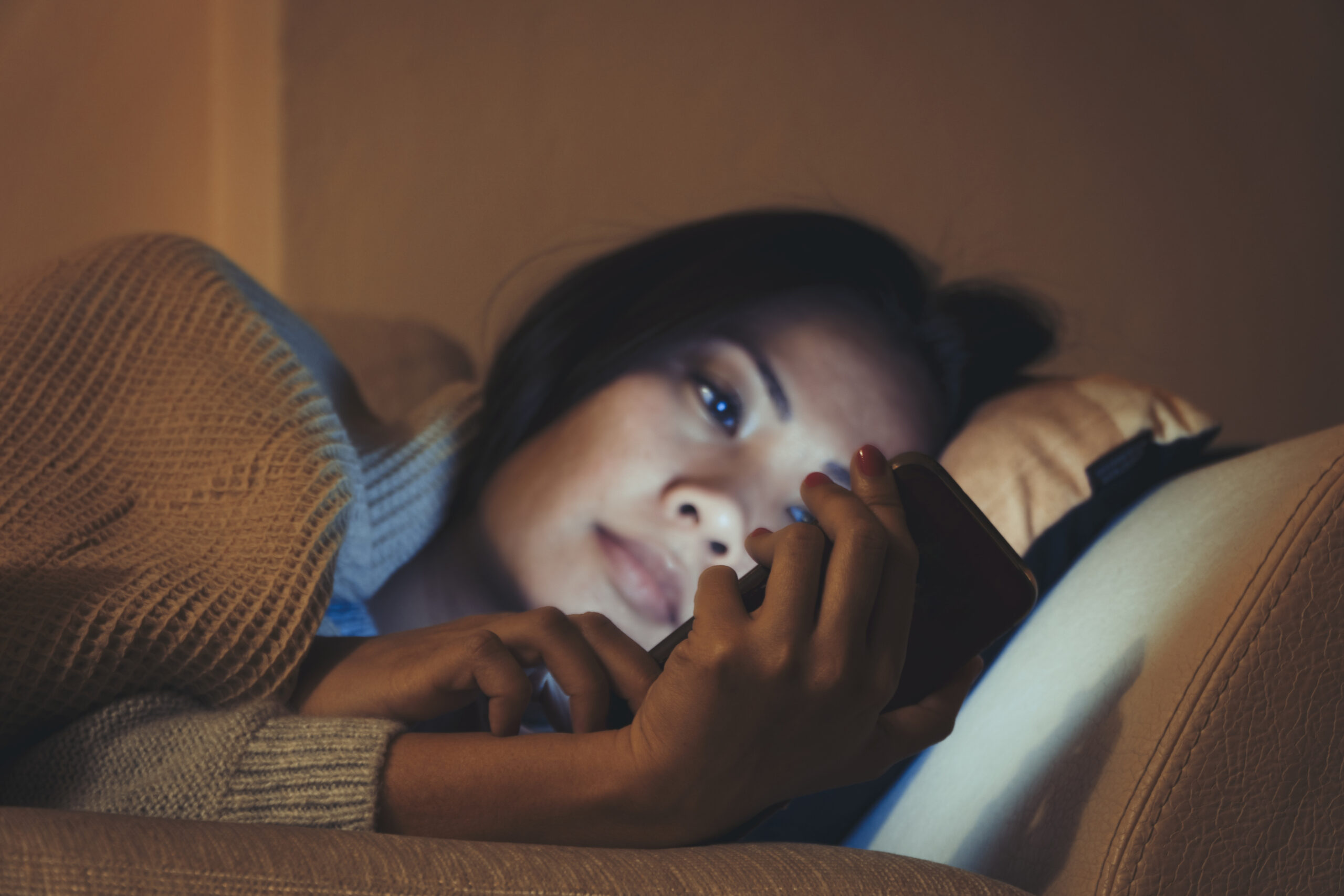 Asian woman using mobile phone on bed